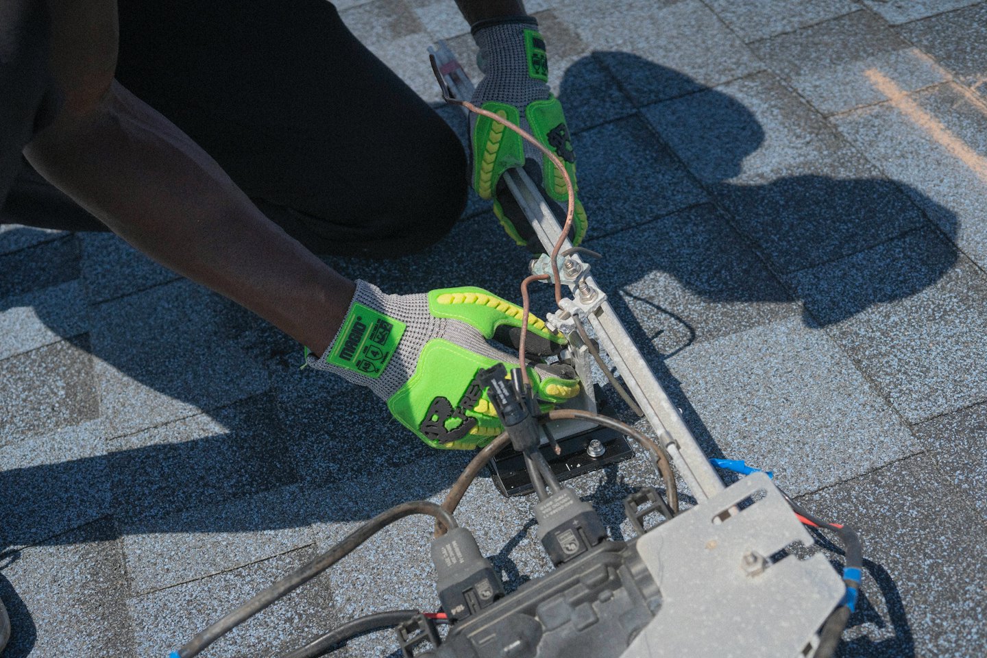 Hands in gloves installing solar panels on a roof.